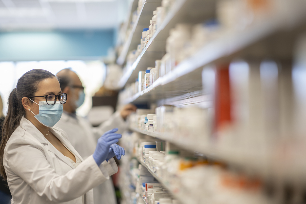 Des pharmaciens dans une allée de médicaments contre la covid-19