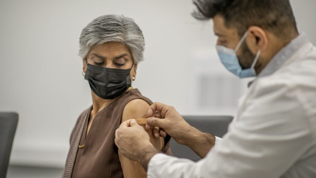 une femme se fait vacciner par un médecin