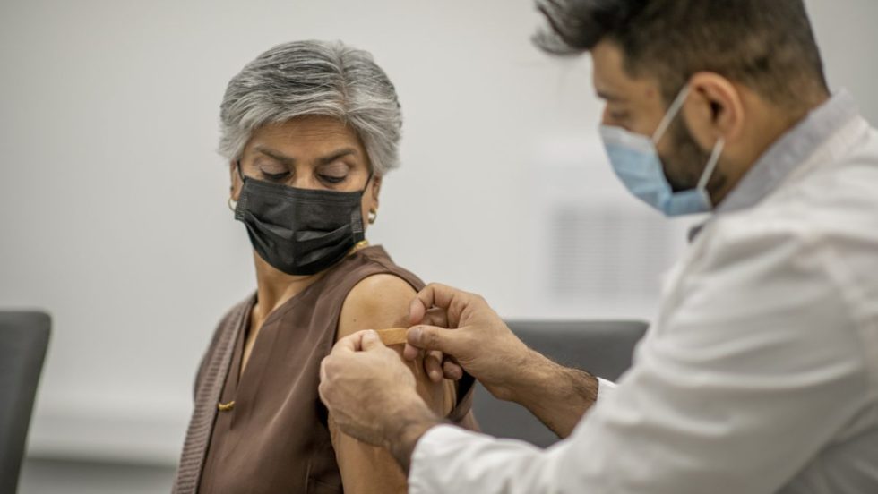 une femme se fait vacciner par un médecin