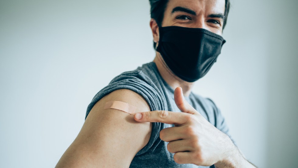 Un jeune homme pointe son bandage après avoir reçu une troisième dose de vaccin contre la covid-19