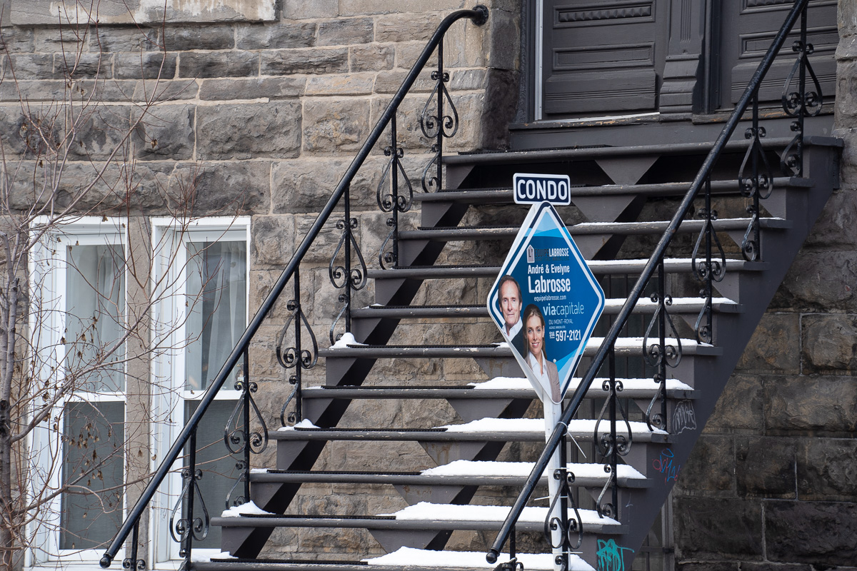 Une affiche à vendre installée devant les escaliers d'un condo de Montréal