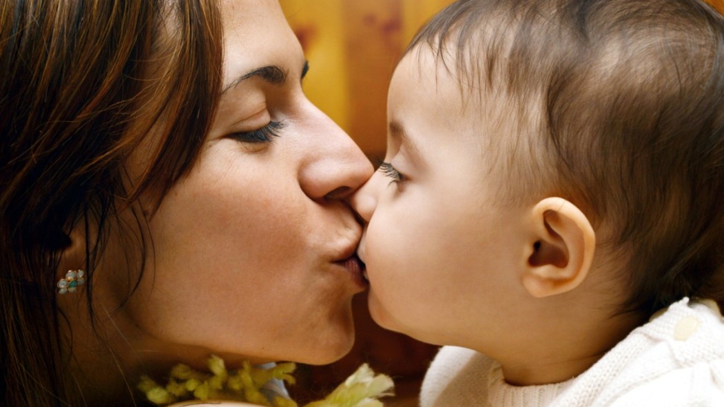 Une mère embrasse son jeune enfant sur la bouche.