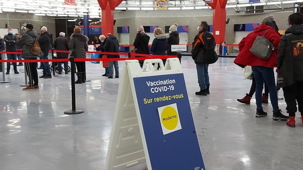 Des personnes de tous âges font la file à l'intérieur de la clinique de vaccination du Stade olympique de Montréal afin de recevoir leur troisième dose.