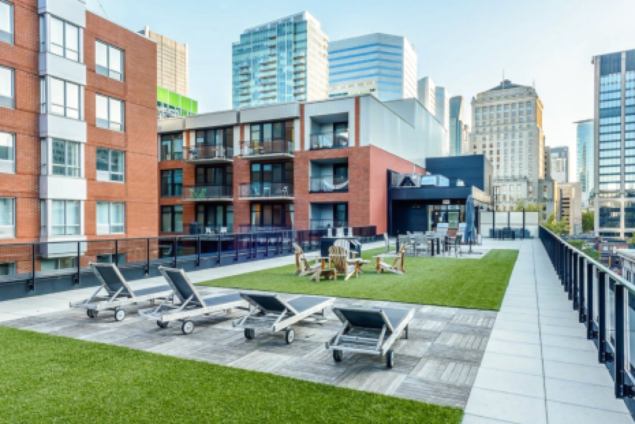 Une terrasse extérieure avec des chaises de jardin et panorama, dans un condo luxueux style urbain, au centre-ville de Montréal.