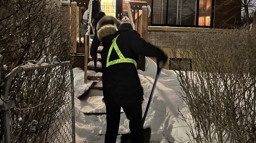 Trois jeunes en train de dégager l'entrée d'une maison.