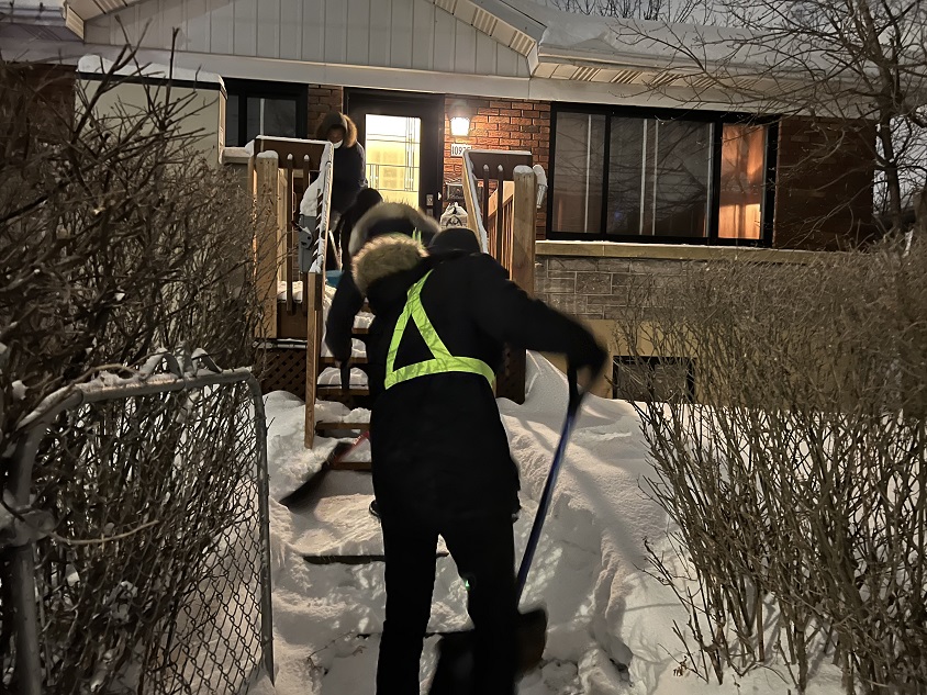 Trois jeunes en train de dégager l'entrée d'une maison.