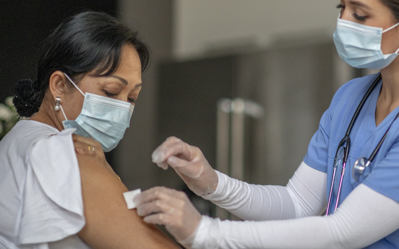 une femme se fait vacciner par une infirmière