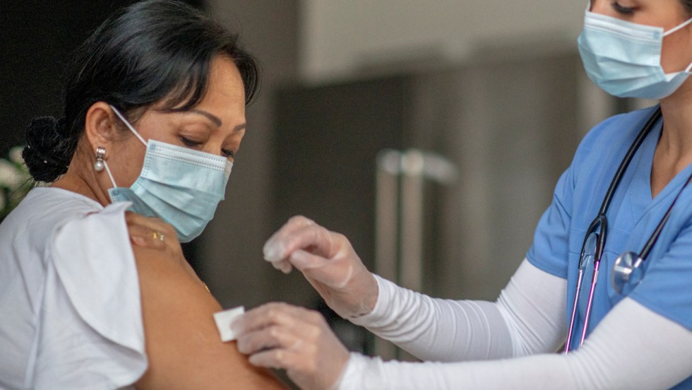 une femme se fait vacciner par une infirmière