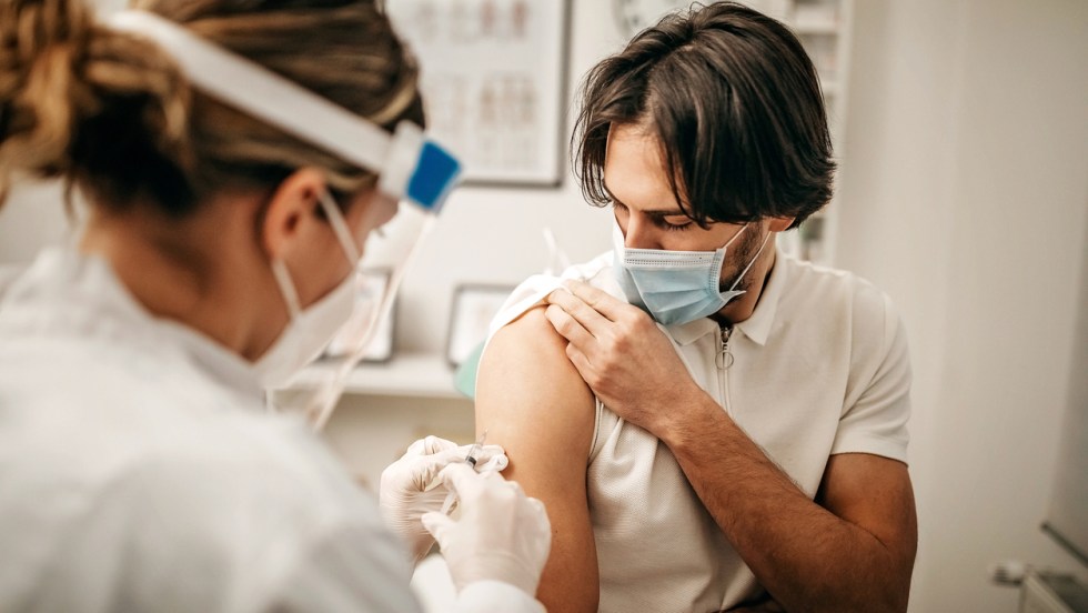 un jeune homme se fait vacciner contre la COVID-19