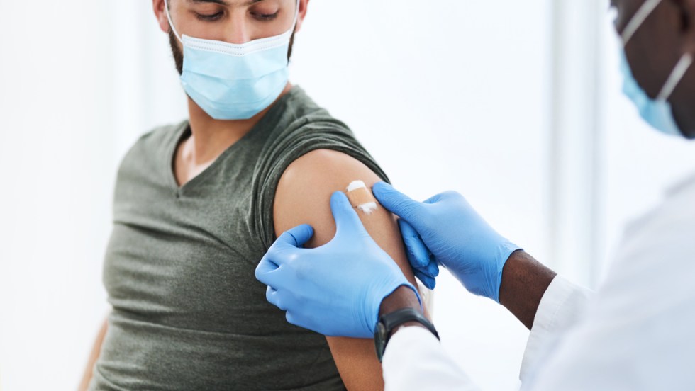 un homme se fait vacciner par un infirmier