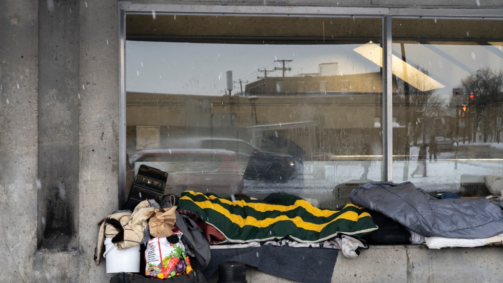Une personne itinérante se repose devant une station de métro de Montréal pendant une vague de froid en hiver.