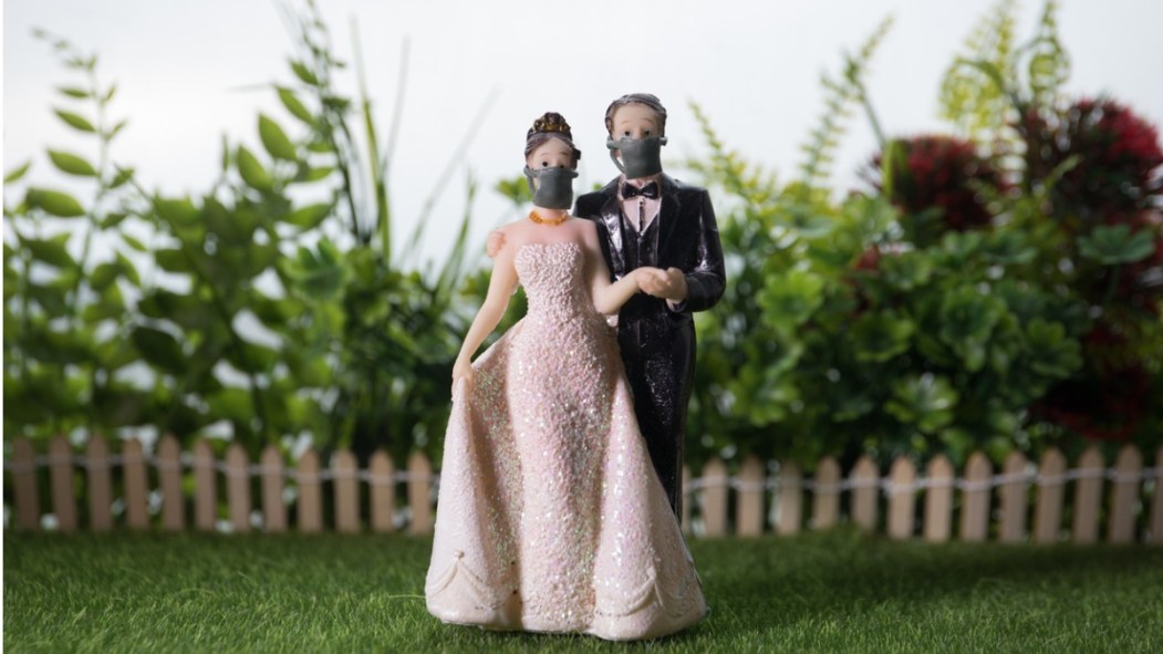 Un petit couple de figurines de mariage dont l'homme et la femme portent un masque.