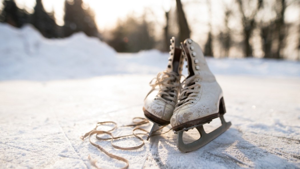 Une paire de patins usés reposent sur une patinoire de glace extérieure en hiver.