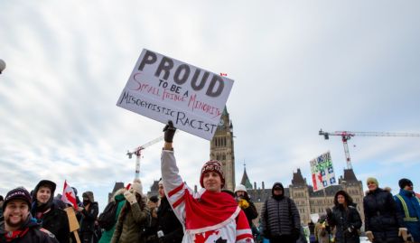 Un manifestant tient une pancarte raciste et misogyne lors de la manifestation de camionneurs à Ottawa