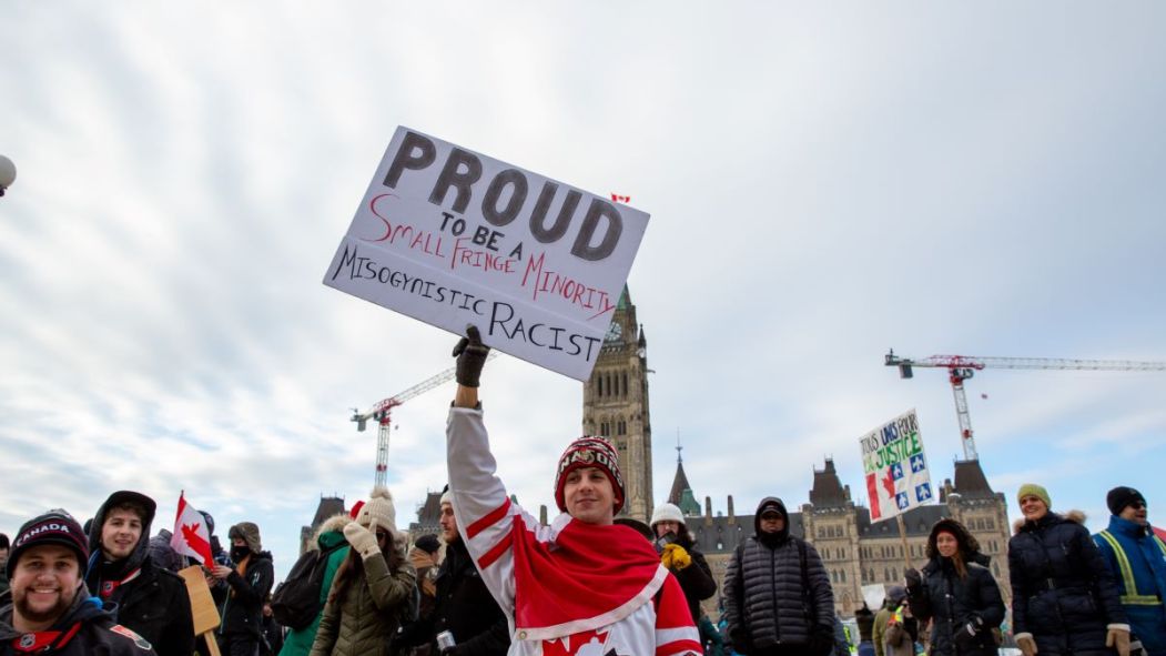 Un manifestant tient une pancarte raciste et misogyne lors de la manifestation de camionneurs à Ottawa