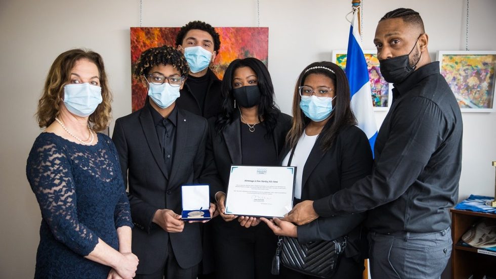 Paule Robitalle et la famille tenant la médaille et le certificat de l'Assemblée nationale.