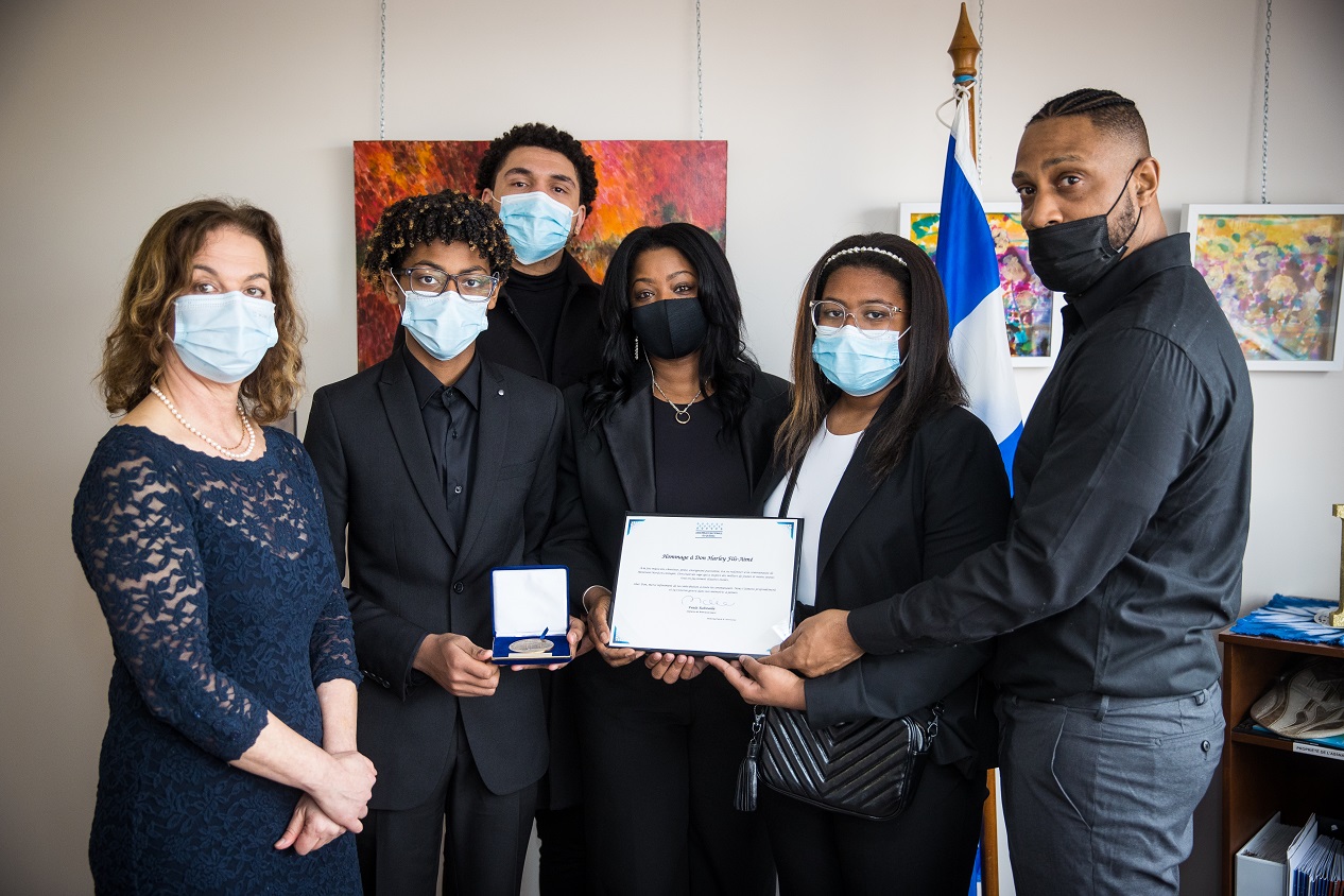 Paule Robitalle et la famille tenant la médaille et le certificat de l'Assemblée nationale.
