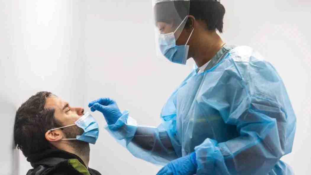 Une infirmière procède à un test de dépistage de la COVID-19 auprès d'un patient masculin.