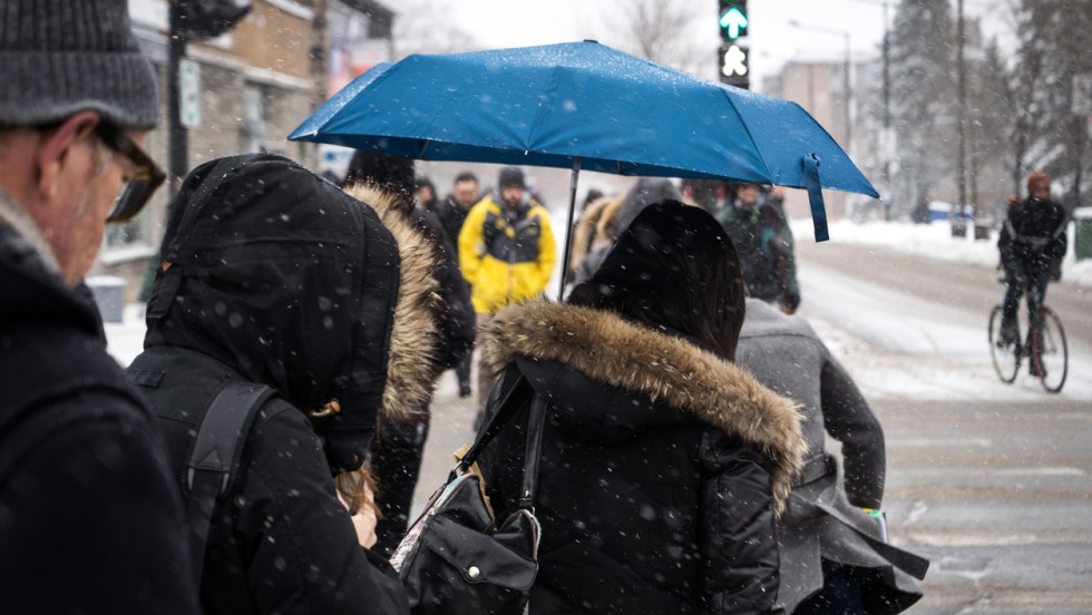 pluie et neige pour la région de Montréal. Des gens traversent une rue avec des parapluies