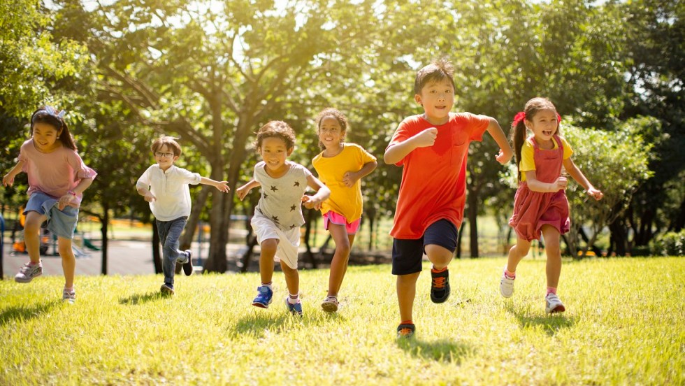 Des enfants courent dans un parc ensoleillé