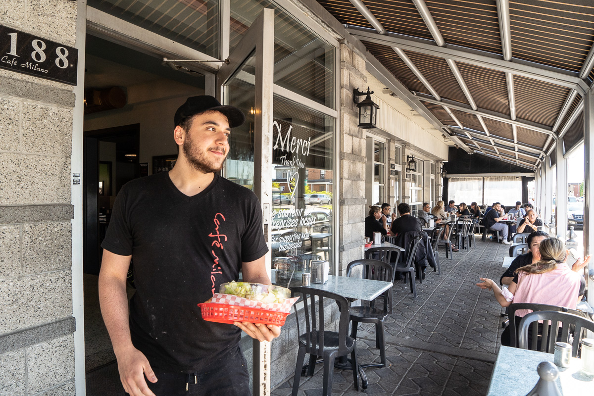 Un serveur apporte un plat sur la terrasse du café Milano, dans l'arrondissement Saint-Léonard.