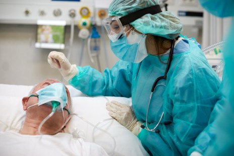 une infirmière porte un uniforme de protection contre la covid-19 et parle à un patient hospitalisé