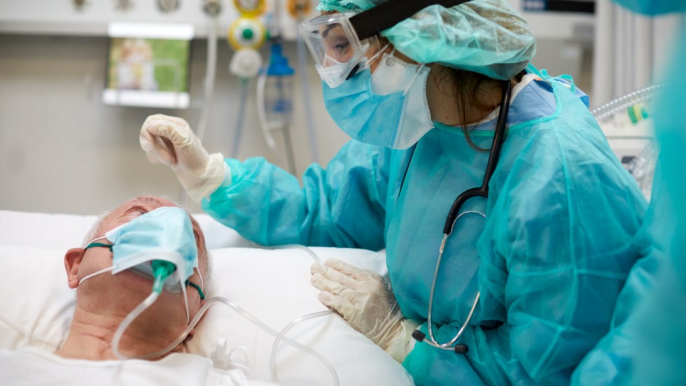 une infirmière porte un uniforme de protection contre la covid-19 et parle à un patient hospitalisé