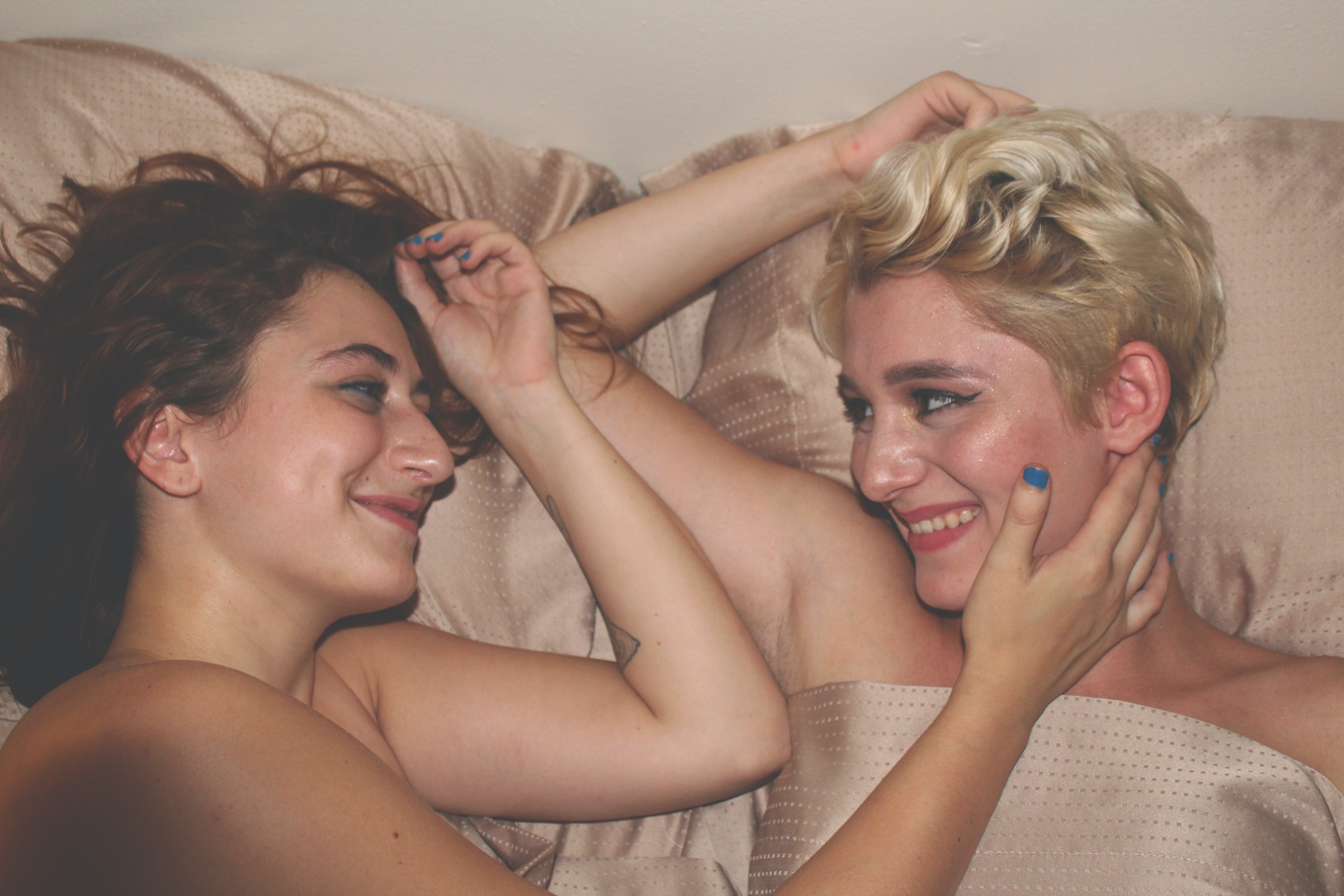 Un couple de femmes couchées dans un lit, se caressant.