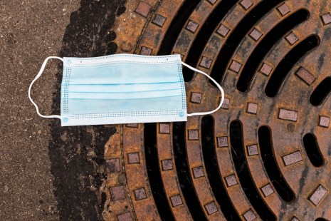 un masque chirurgical est posé sur une bouche d'égout pour illustrer le dépistage de la covid-19 dans les eaux usées.