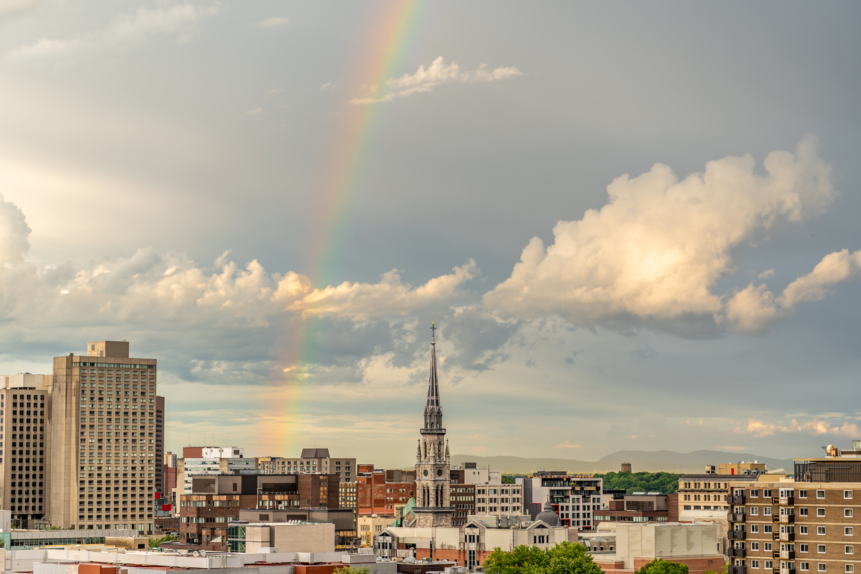 Un arc-en-ciel surplombe le skyline de Montréal en été pendant un coucher de soleil.