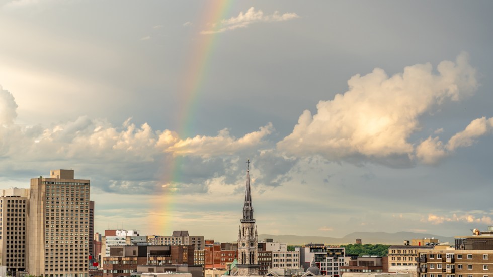 Un arc-en-ciel surplombe le skyline de Montréal en été pendant un coucher de soleil.