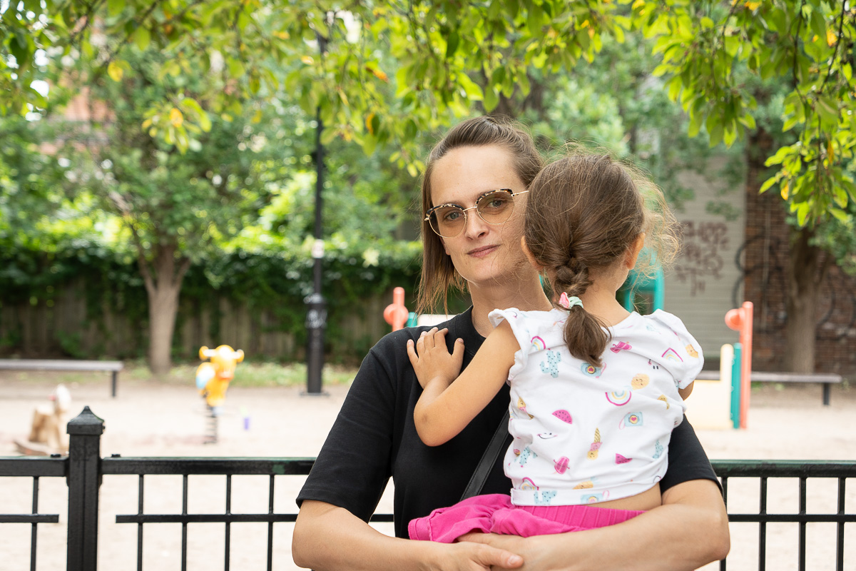 Une femme tient un enfant dvant un parc de Montréal. Maritchu Ithurriague vit à sa famille à l'hôtel depuis que leur appartement à été incendié, faute de logements adéquats à Montréal.