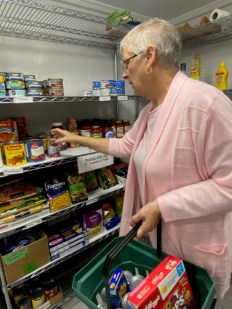 Une bénévole de HOPE ramassant des denrées alimentaires dans une étagère.