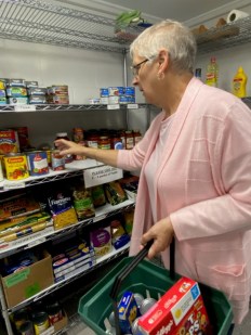 Une b&eacute;n&eacute;vole de HOPE ramassant des denr&eacute;es alimentaires dans une &eacute;tag&egrave;re.