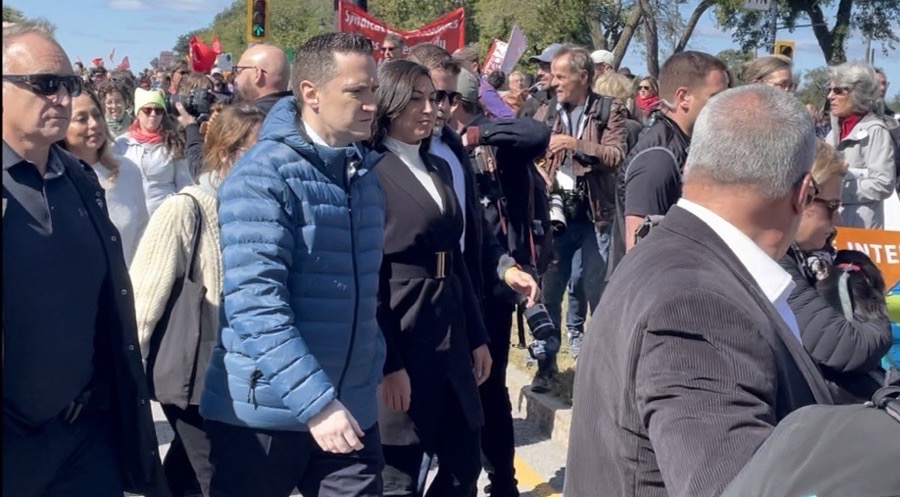 Le ministre de l'Environnement Benoit Charette entouré de manifestants, de staff politique et de policiers de la Sûreté du Québec lors de la manifestation pour le climat.