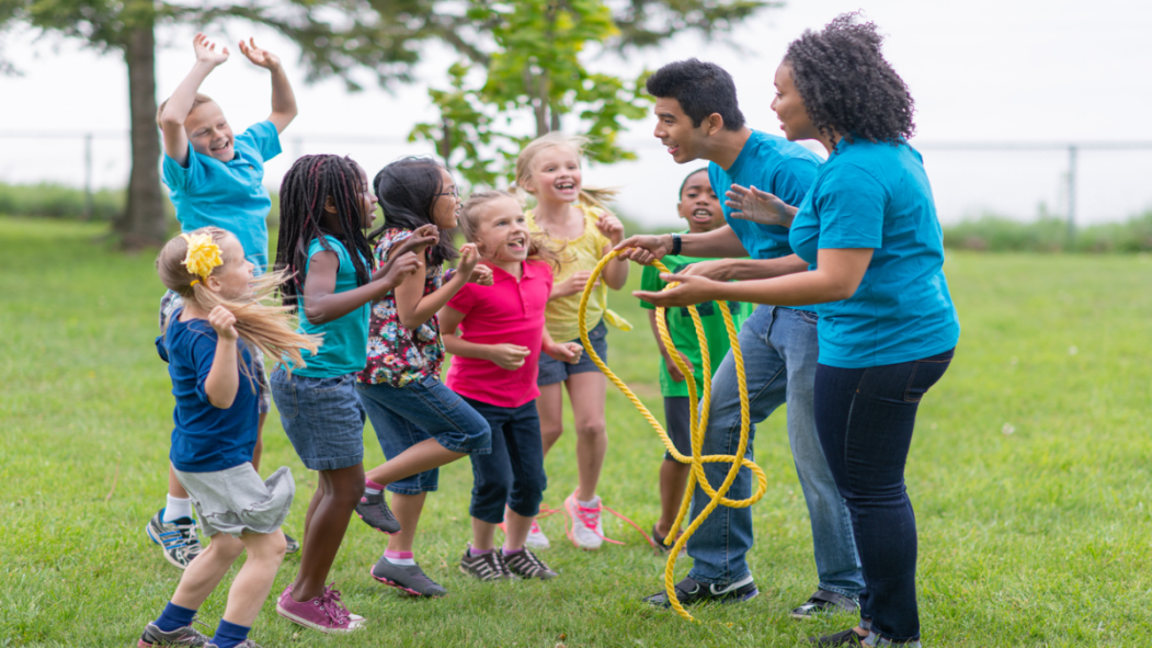 Des animateurs de camp de jour jouent avec des enfants dans un parc.