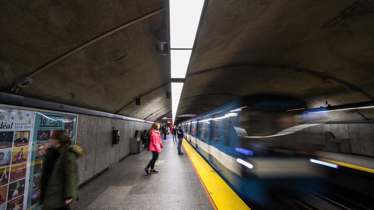 Un train de métro arrive au quai pendant que des passagers l'attendent.