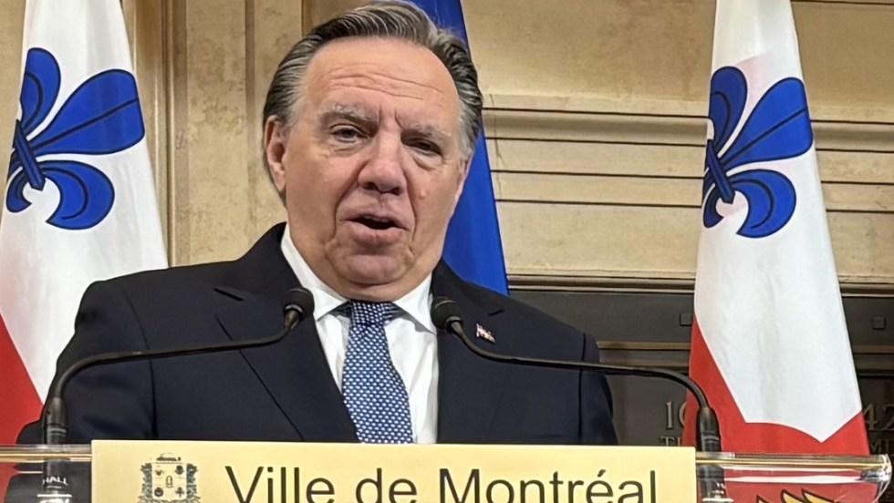 François Legault à l'hôtel de ville devant des drapeaux de Montréal et du Québec.