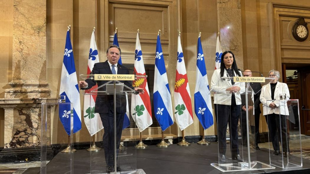 François Legault et Soraya Martinez Ferrada debouts devant des drapeaux de Québec et de Montréal lors d'une conférence de presse.