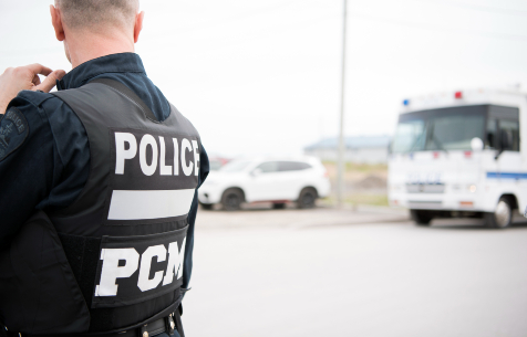 Un policier vu de dos devant un poste de commandement du SPVM.