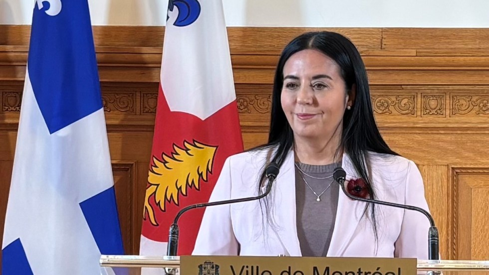 Soraya Martinez Ferrada en point de presse à l'hôtel de ville de Montréal devant des drapeaux du Québec et de Montréal.