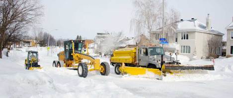 Des déneigeuses soufflent la neige dans une rue locale de Laval.