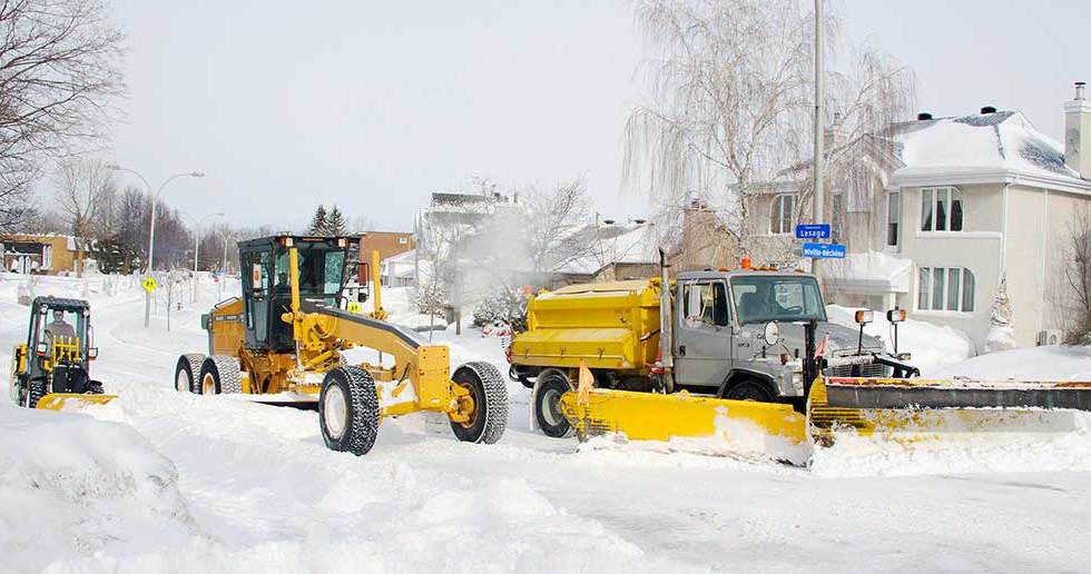 Des déneigeuses soufflent la neige dans une rue locale de Laval.