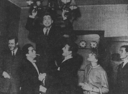 Photo num&eacute;ris&eacute;e en noir et blanc des membres du collectif Les Bozos qui rigolent dans leur bo&icirc;te &agrave; chanson. Un des membres est suspendu &agrave; un luminaire pendant que deux autres le tiennent.