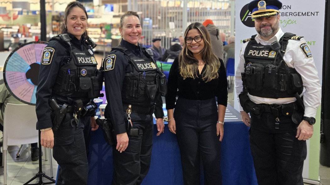 Trois policières et un policier devant un kiosque aux Halles d'Anjou pour une activité de sensibilisation à la violence conjugale.