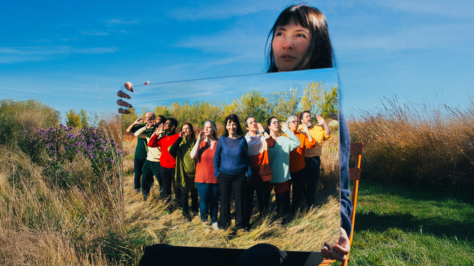 Une femme tient un portrait du Choeur Baobab dans un champ.