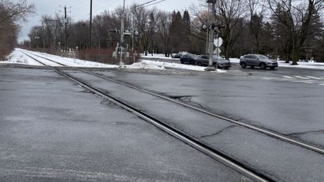 Une voie ferrée traverse une intersection routière près de l'hôtel de ville de Boucherville, en hiver.