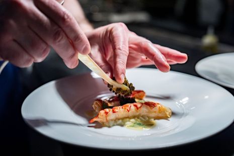 Un chef place des aliments dans une assiette pour un plat gastronomique pendant Montr&eacute;al en Lumi&egrave;re.