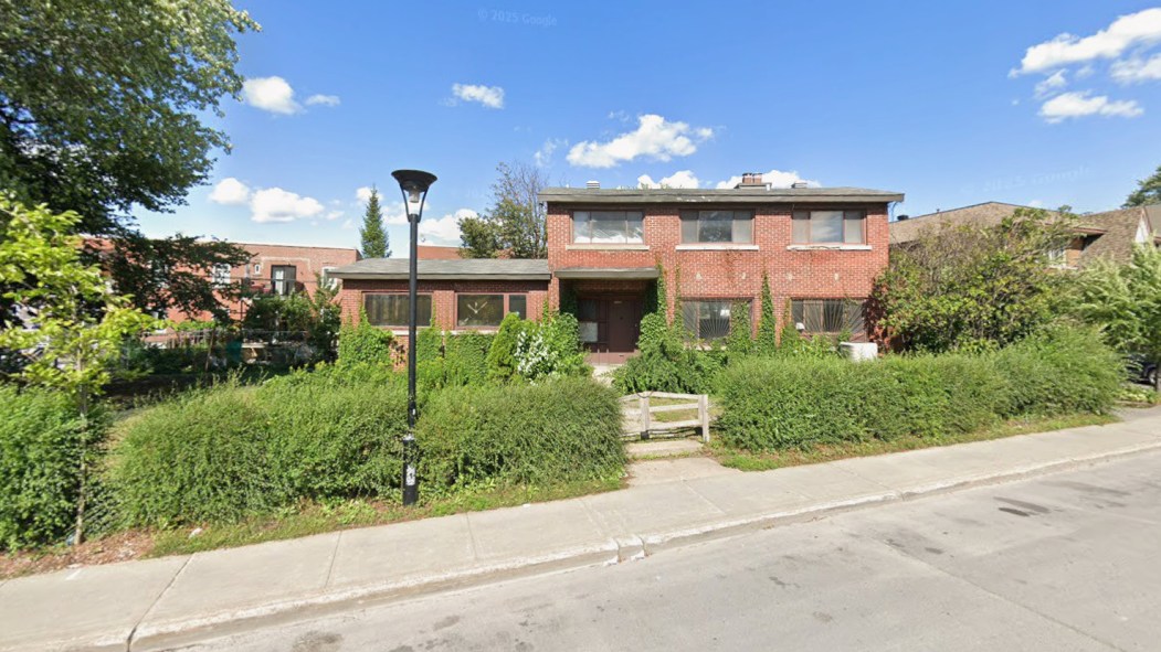 Une maison unifamiliale en brique rouge avec une haie.