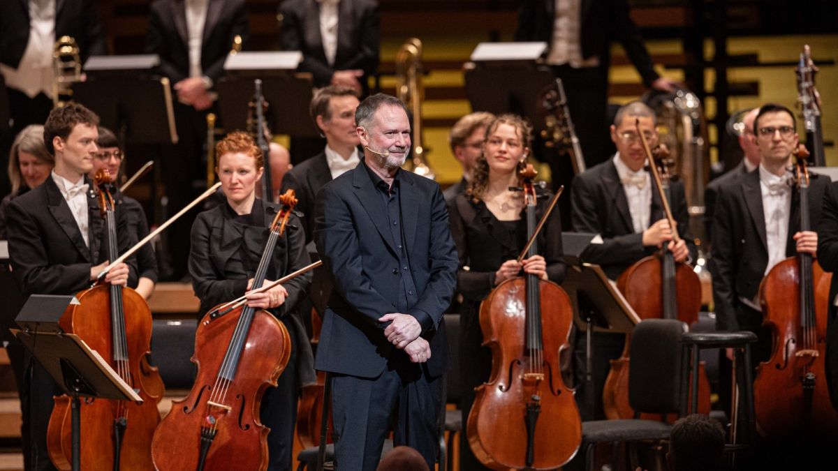 François Pérusse se tient devant les musiciens de l'Orchestre symphonique de Montréal pendant le spectacle Pérusse symphonique.